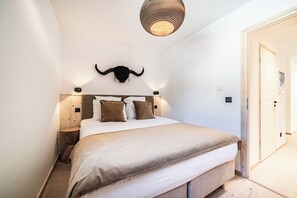 Ein Schlafzimmer mit einem Bett, einem Wandbild eines Stiers, Nachttischlampen und einer Tür.