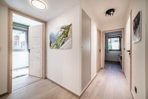 Un corridoio con pavimento in legno, una porta che dà su un balcone e un'opera d'arte appesa al muro.