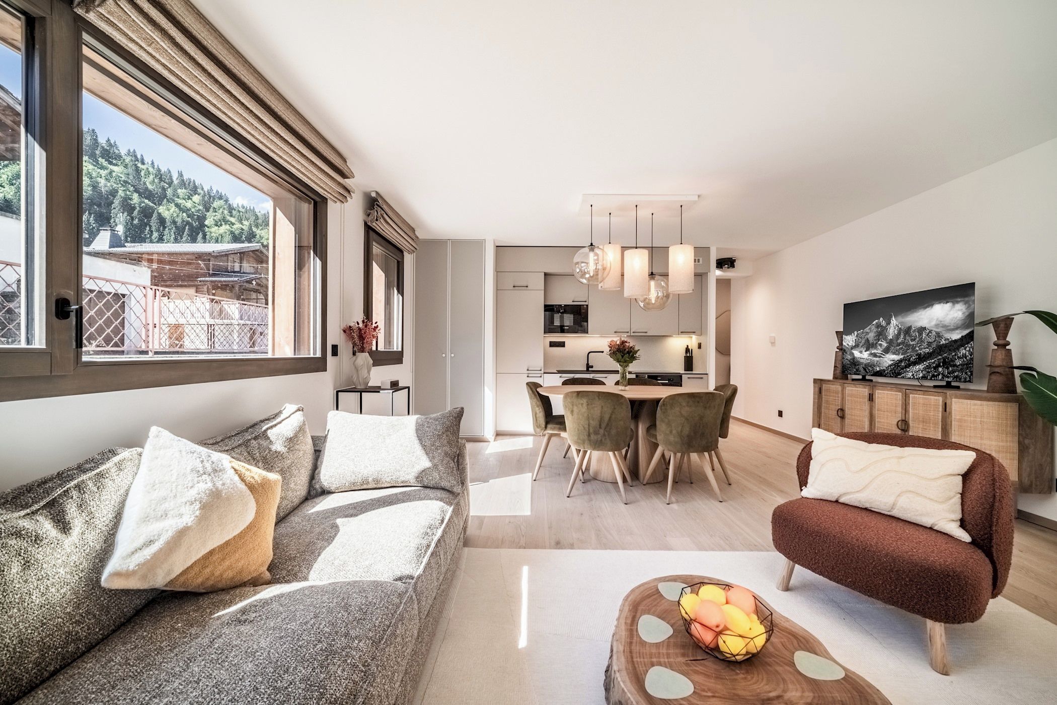 A modern living room with a sofa, armchair, and coffee table, a dining area with chairs, and a kitchen in the background.