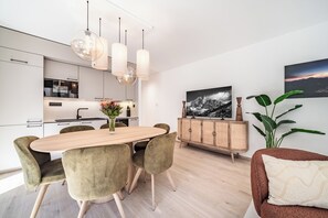 A modern kitchen with white cabinets, a Bosch oven, and a dining area with a wooden table and velvet chairs. - Laverock – Garden | Parking | Near Lifts | Morzine (Morzine)