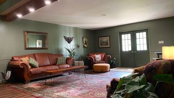 A living room with a brown leather sofa, a patterned rug, and a green wall.