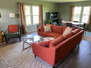 A living room with a sofa, armchair, coffee table, and a bookshelf.