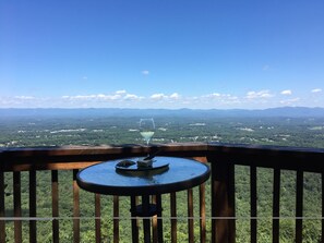 Ein Balkon mit Tisch und einem Glas Weißwein, mit Blick auf eine Berglandschaft.