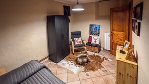 A cozy room with a sofa, a chair, a cabinet, a cowhide rug, and a wooden door. - A Casa di Ayra (Rino)