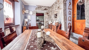 Un comedor rústico con una mesa de madera, bancos y una pared de piedra.