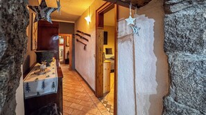A narrow hallway with stone walls, a wooden door, and a tiled floor. - A Casa di Ayra (Rino)
