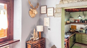 A rustic kitchen with wooden cabinets, a microwave, and a coffee maker. - A Casa di Ayra (Rino)