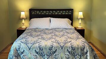 A bed with a patterned bedspread, two bedside lamps, and a ceiling fan.