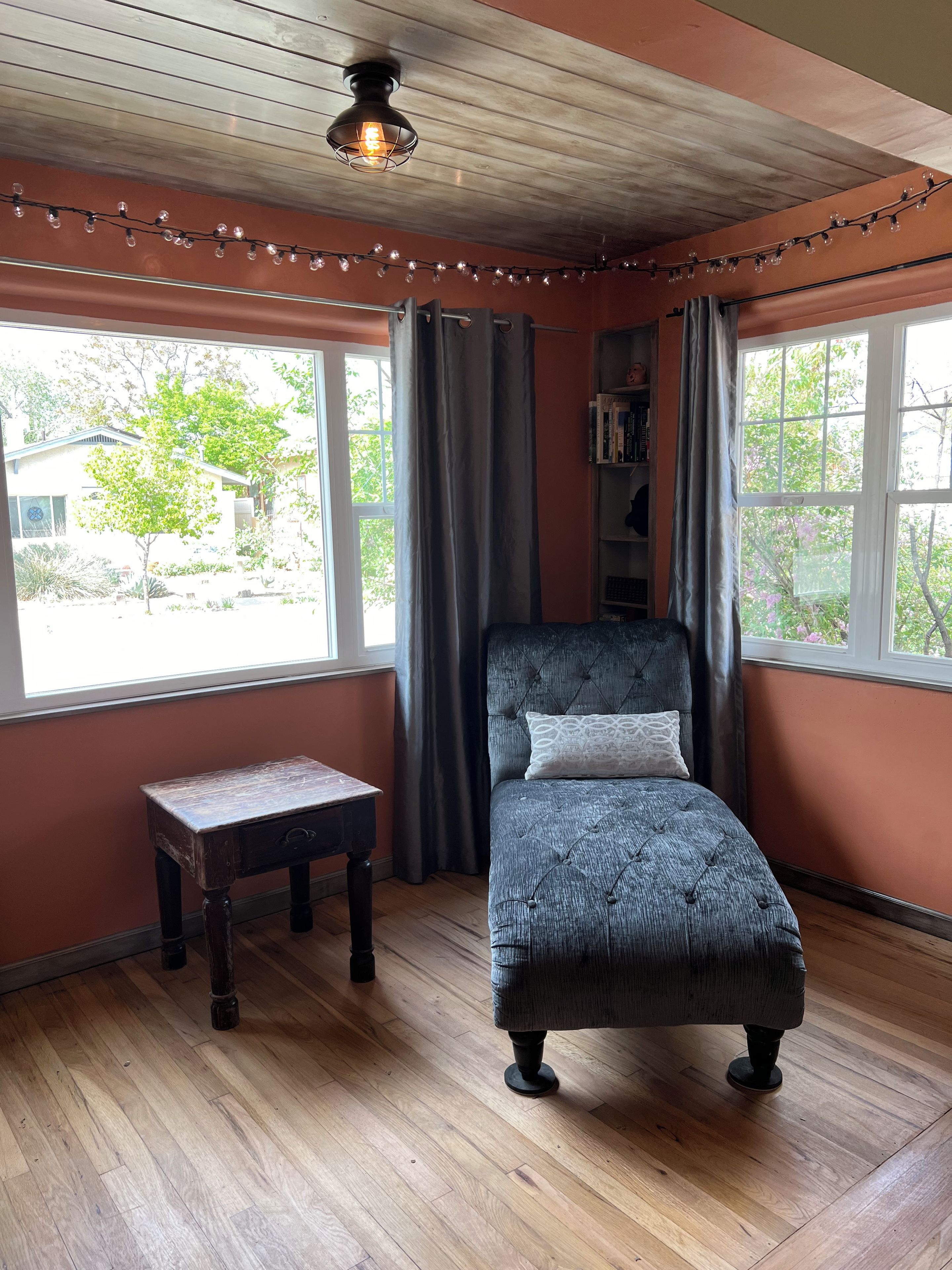 A room with a bed, a small table, and a window with curtains.