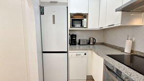 A compact kitchen with a refrigerator, microwave, coffee maker, toaster, and a small dishwasher. - AP178 Capistrano Playa 601 (Nerja)