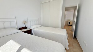 A room with two beds, a nightstand, a lamp, and a wardrobe. - AP178 Capistrano Playa 601 (Nerja)