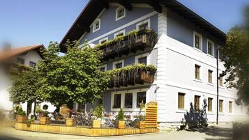 A multi-story building with balconies, a central courtyard with plants, and a street view.