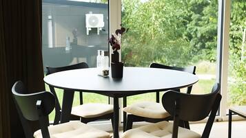A round table with four chairs, a pendant light, and a vase with flowers.