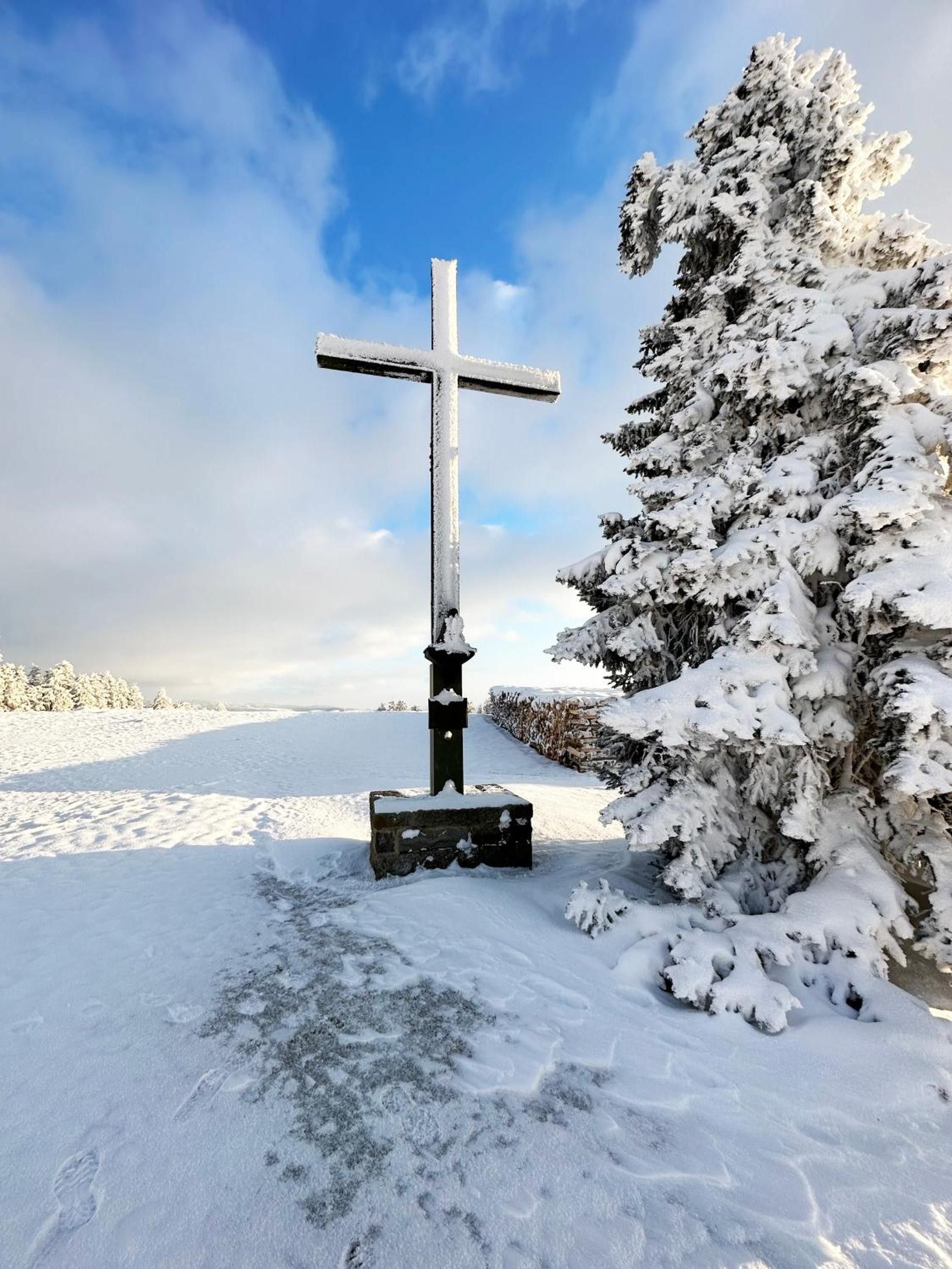 Paesaggio innevato con un monumento a forma di croce.