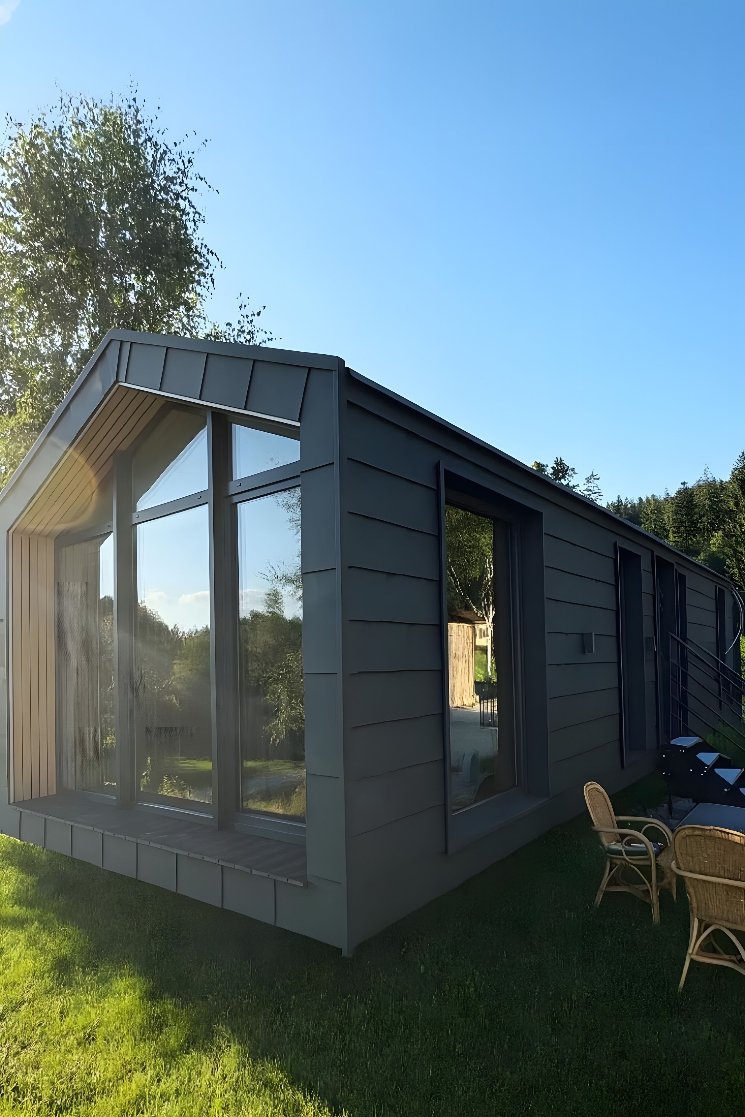 Ett modernt hus med stora fönster och en veranda.