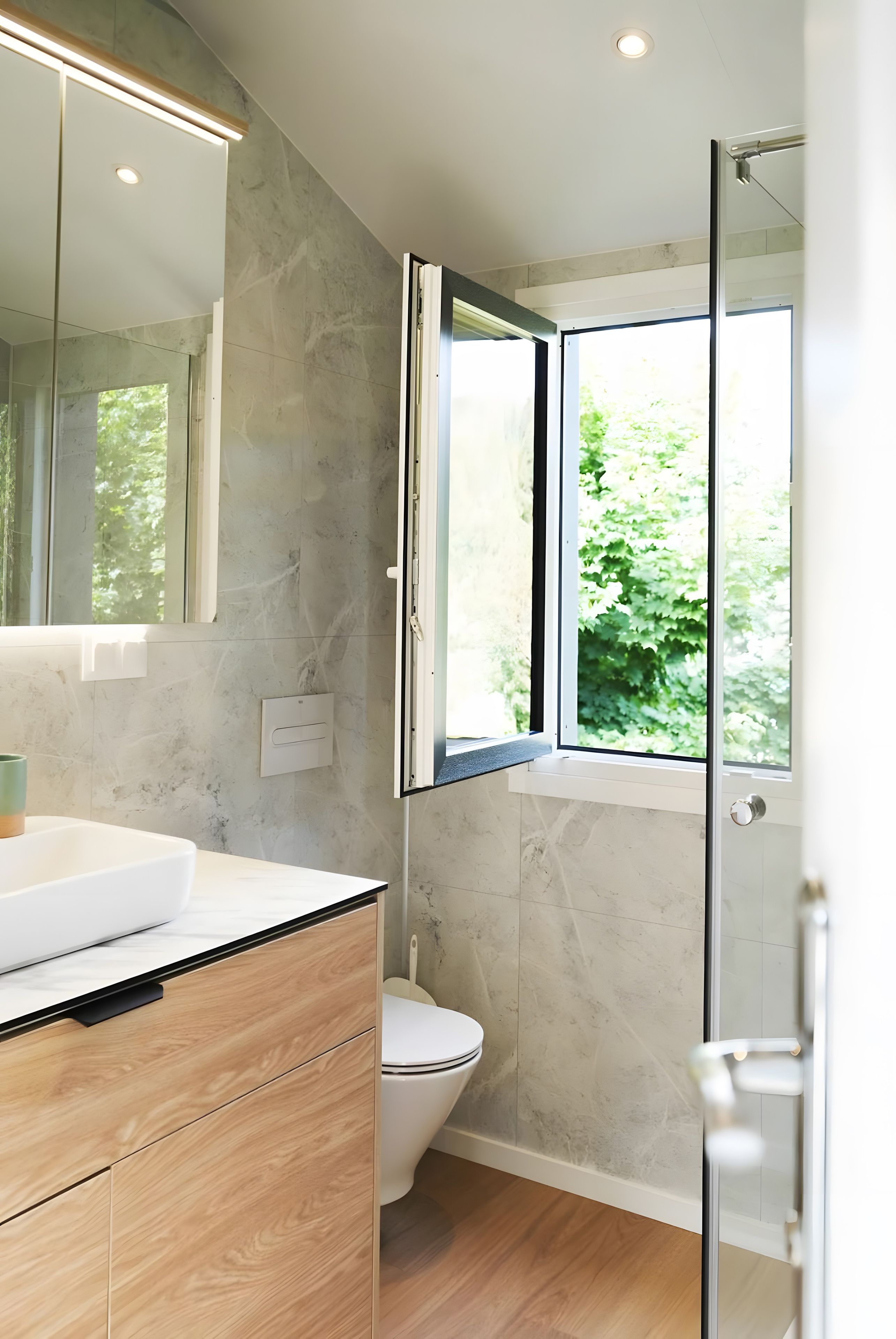 Ein modernes Badezimmer mit Marmorwand, Waschtisch aus Holz, Toilette und Duschkabine aus Glas.