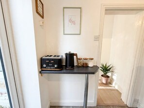 Eine Küchenzeile mit einem schwarzen Toaster, einer Kaffeemaschine und Gläsern auf einem kleinen Tisch.