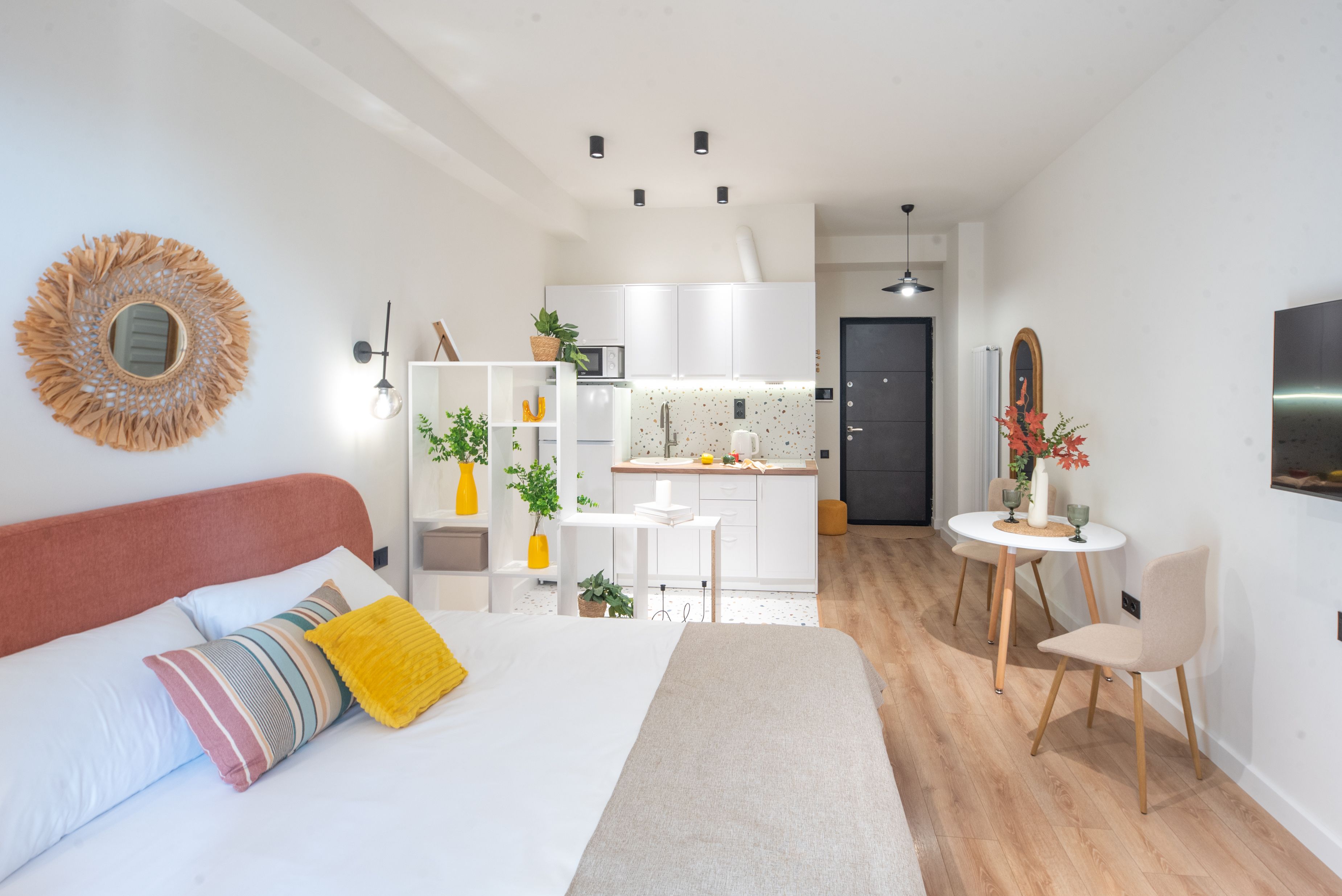 A modern, compact living space with a bed, kitchenette, and seating area.