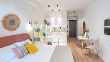 A modern, compact living space with a bed, kitchenette, and seating area.