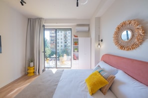 A modern bedroom with a large bed, a balcony with a view of buildings, and a round mirror on the wall. - HB apartments Chkhikvadze (T'bilisi)
