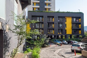 A modern multi-story building with balconies, a parking area, and a dirt path. - HB apartments Chkhikvadze (T'bilisi)