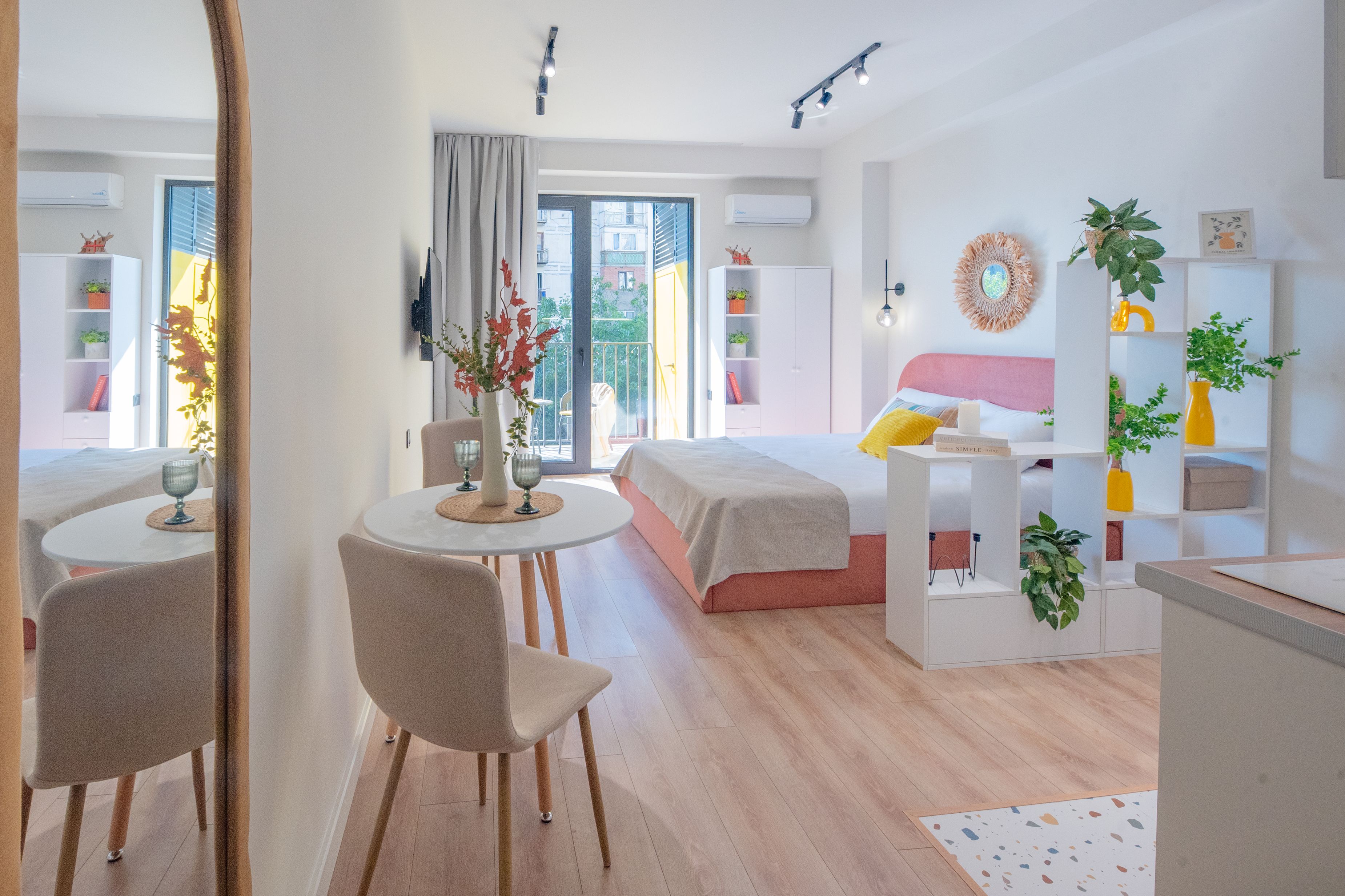 A modern hotel room with a bed, a desk, a chair, and a dining area.