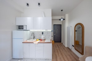A compact kitchen with white cabinets, a microwave, a kettle, and a sink. - HB apartments Chkhikvadze (T'bilisi)