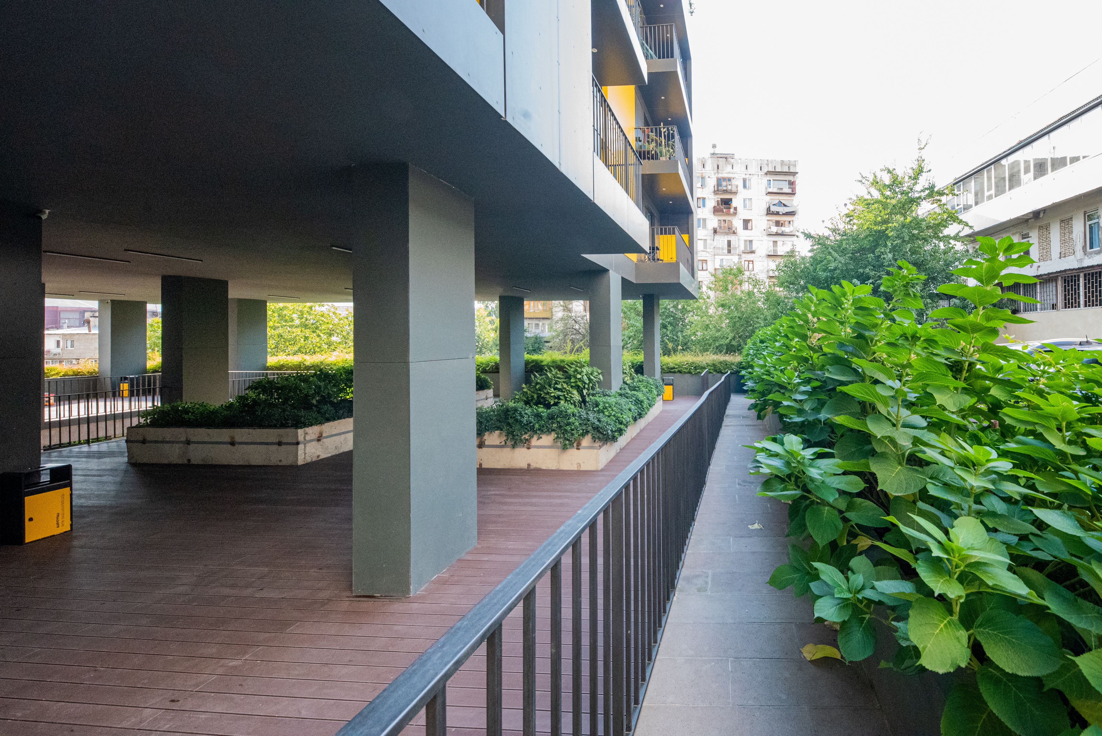An outdoor area with a covered walkway, concrete pillars, and a metal railing.