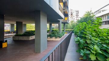 An outdoor area with a covered walkway, concrete pillars, and a metal railing.