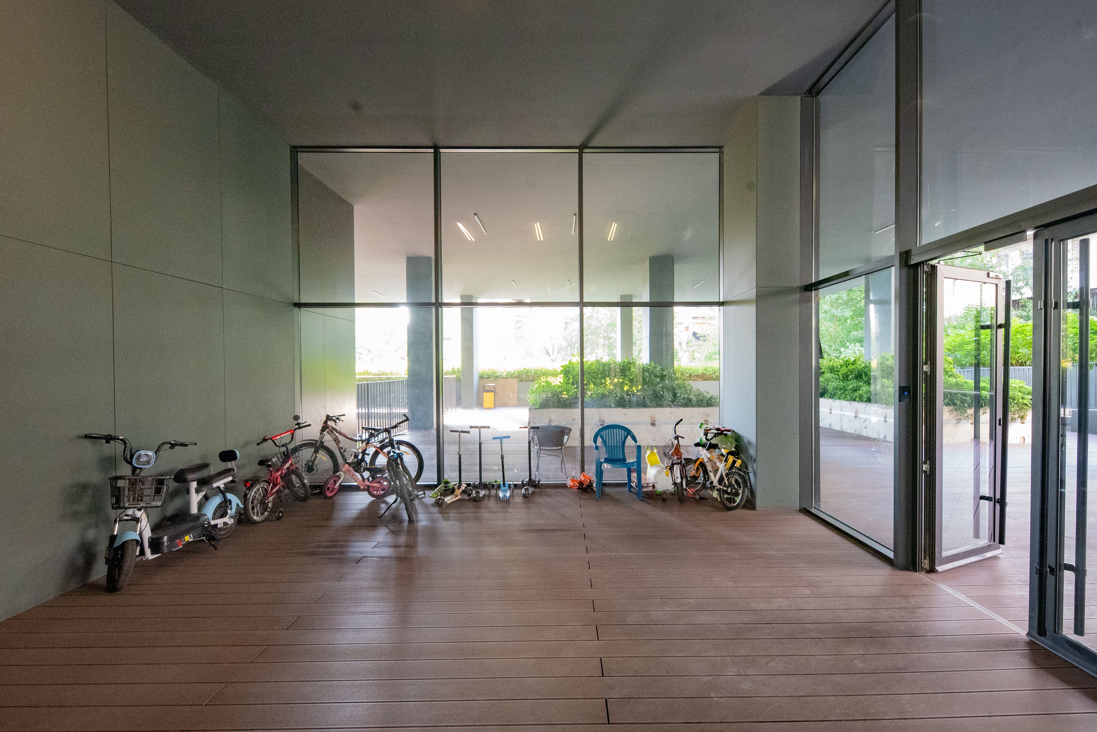 A room with a wooden floor, large windows, and bicycles parked against the wall.