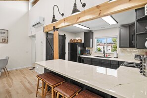 A modern kitchen with a large island, black appliances, and a view of the outside.
