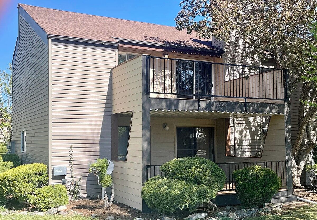 A two-story residential building with a balcony, a satellite dish, and a mailbox.