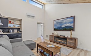 Een moderne woonkamer met een bank, salontafel, open haard en een groot schilderij aan de muur.