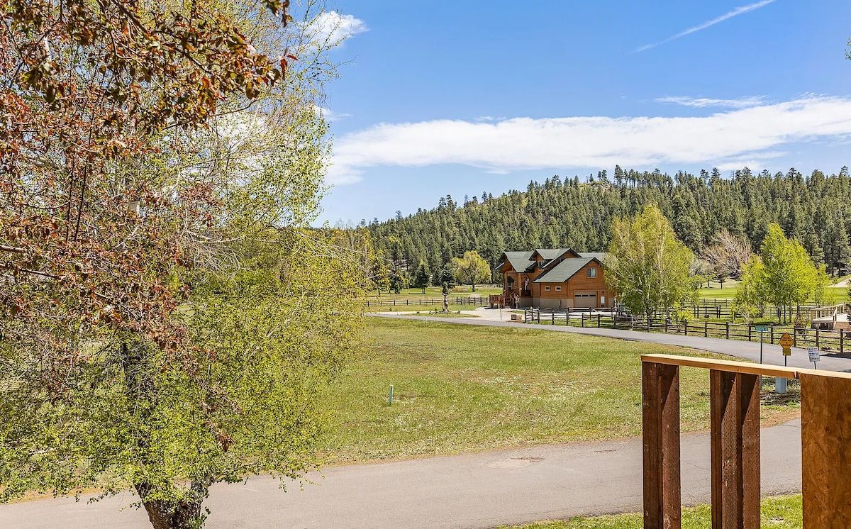 A lodge with a wooden exterior, a paved driveway, and a forested backdrop.