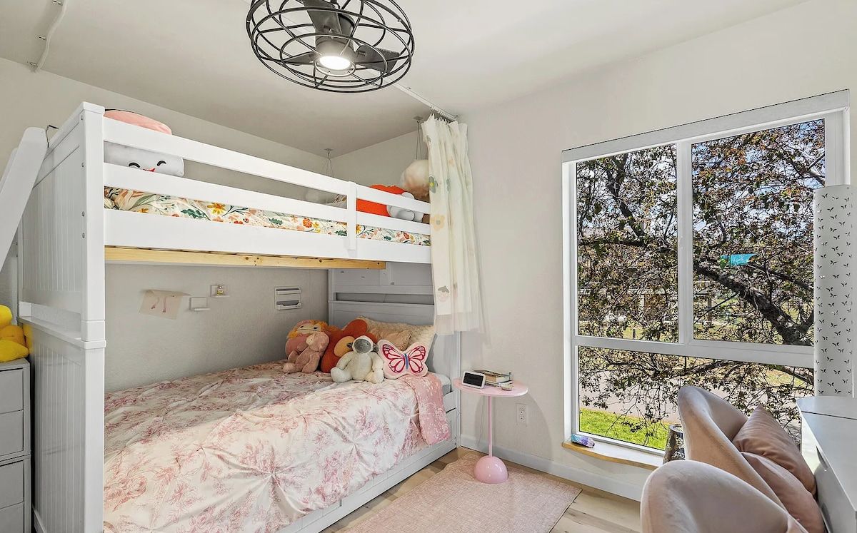 Ein Schlafraum mit Etagenbett, einem Fenster, einem kleinen Tisch und einem Stuhl.
