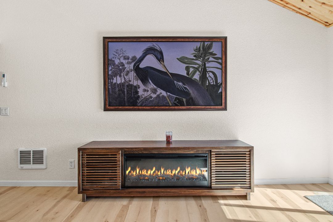 Una chimenea de diseño moderno, con un cuadro enmarcado encima y piso de madera.