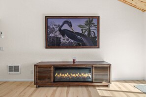 A fireplace with a modern design, a framed painting above it, and a wooden floor.