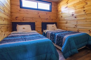 A cabin with two beds, wooden walls, and a window.