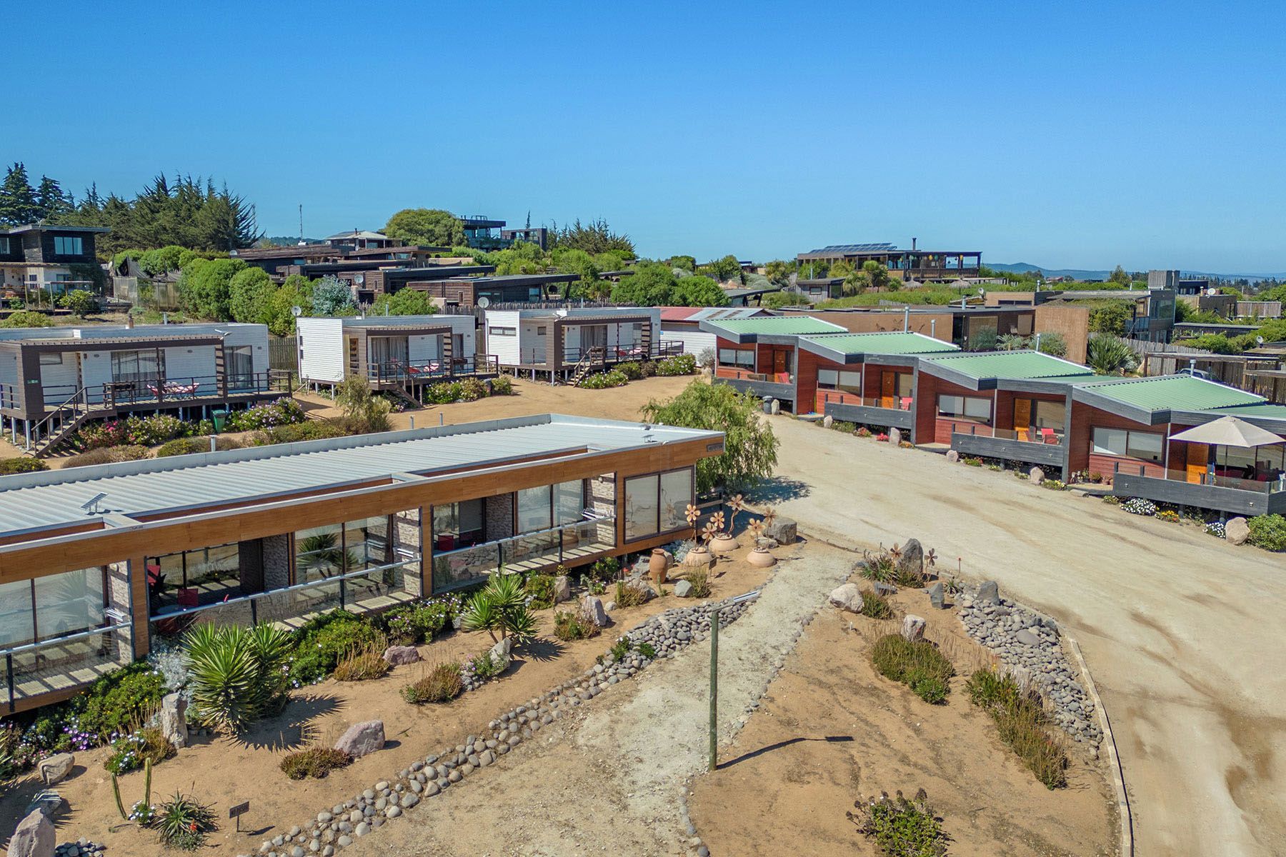 Zona residencial con casas modernas, un camino de tierra y cielo despejado.