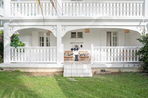 A two-story house with a porch, white railings, and a small garden area. - Savannah Élégance - Chez Soi, côté Plage (Saint-Francois)
