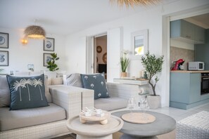 A modern living room with a sofa, coffee table, and a dining area with a round table. - Savannah Élégance - Chez Soi, côté Plage (Saint-Francois)