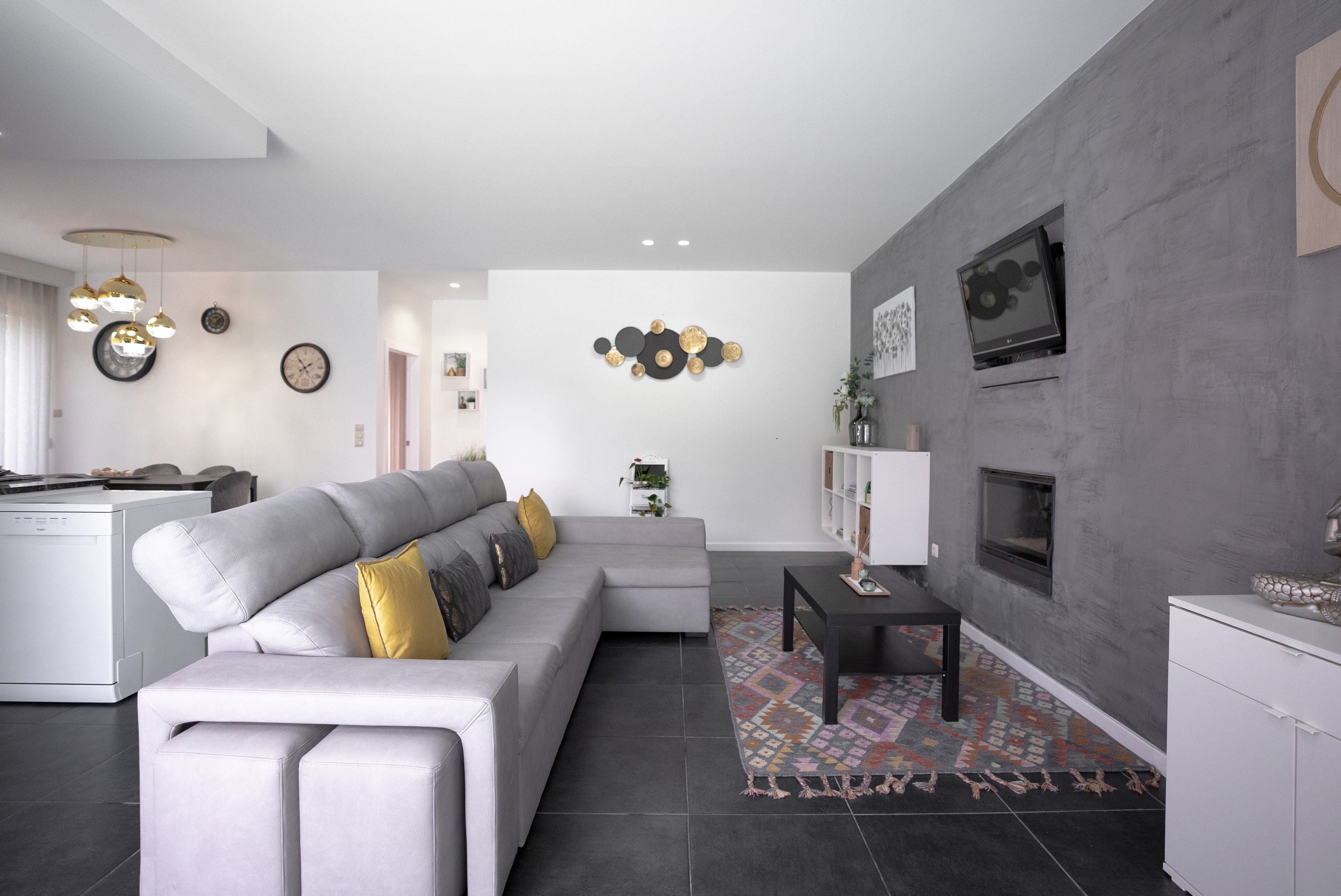 A modern living room with a grey sectional sofa, a small black coffee table, and a patterned rug.