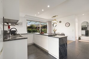 Una cocina moderna con lavavajillas integrado, un lavamanos de acero inoxidable y un amplio ventanal con vistas a un jardín.