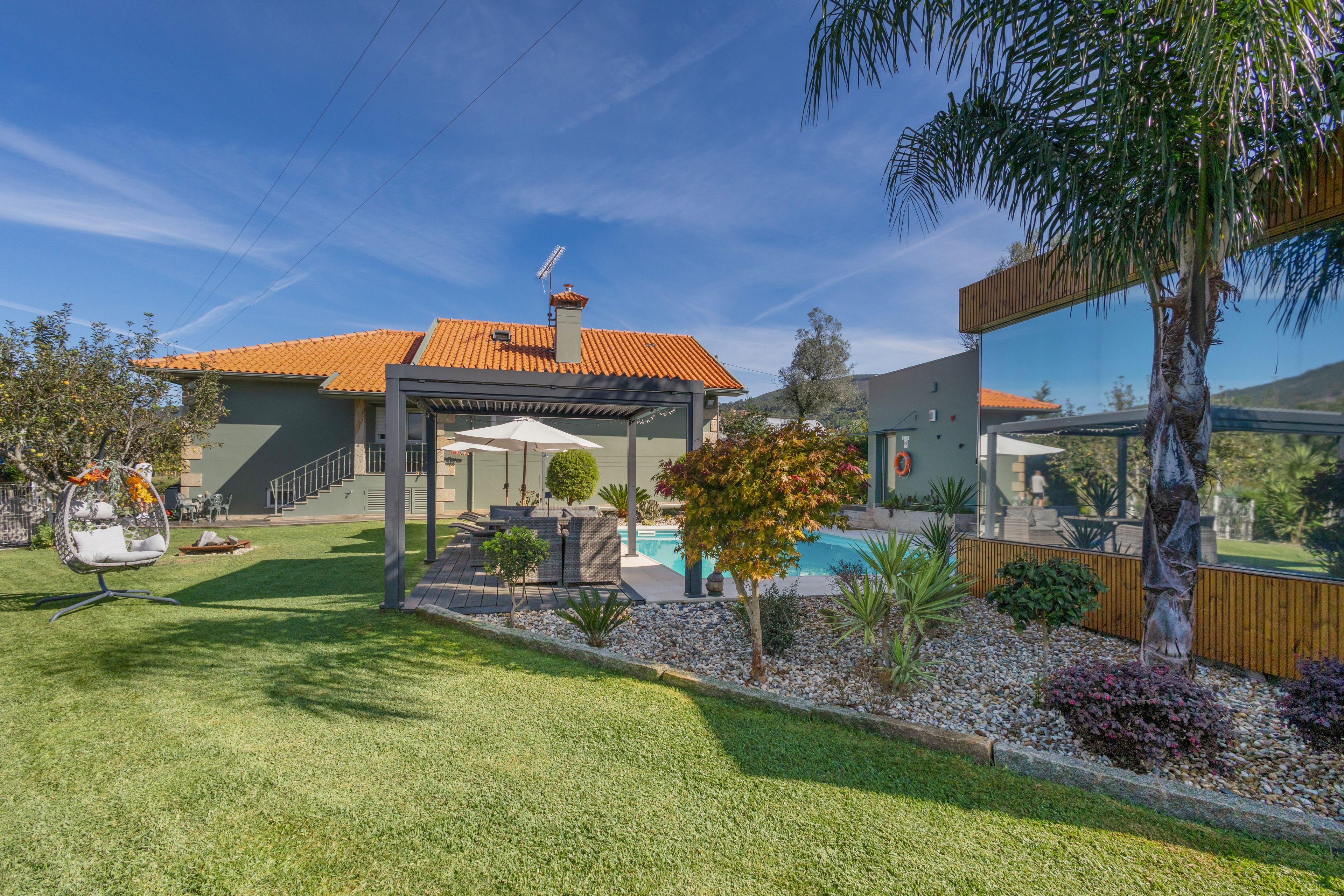 Propiedad residencial con piscina, zona de estar exterior y terraza cubierta.