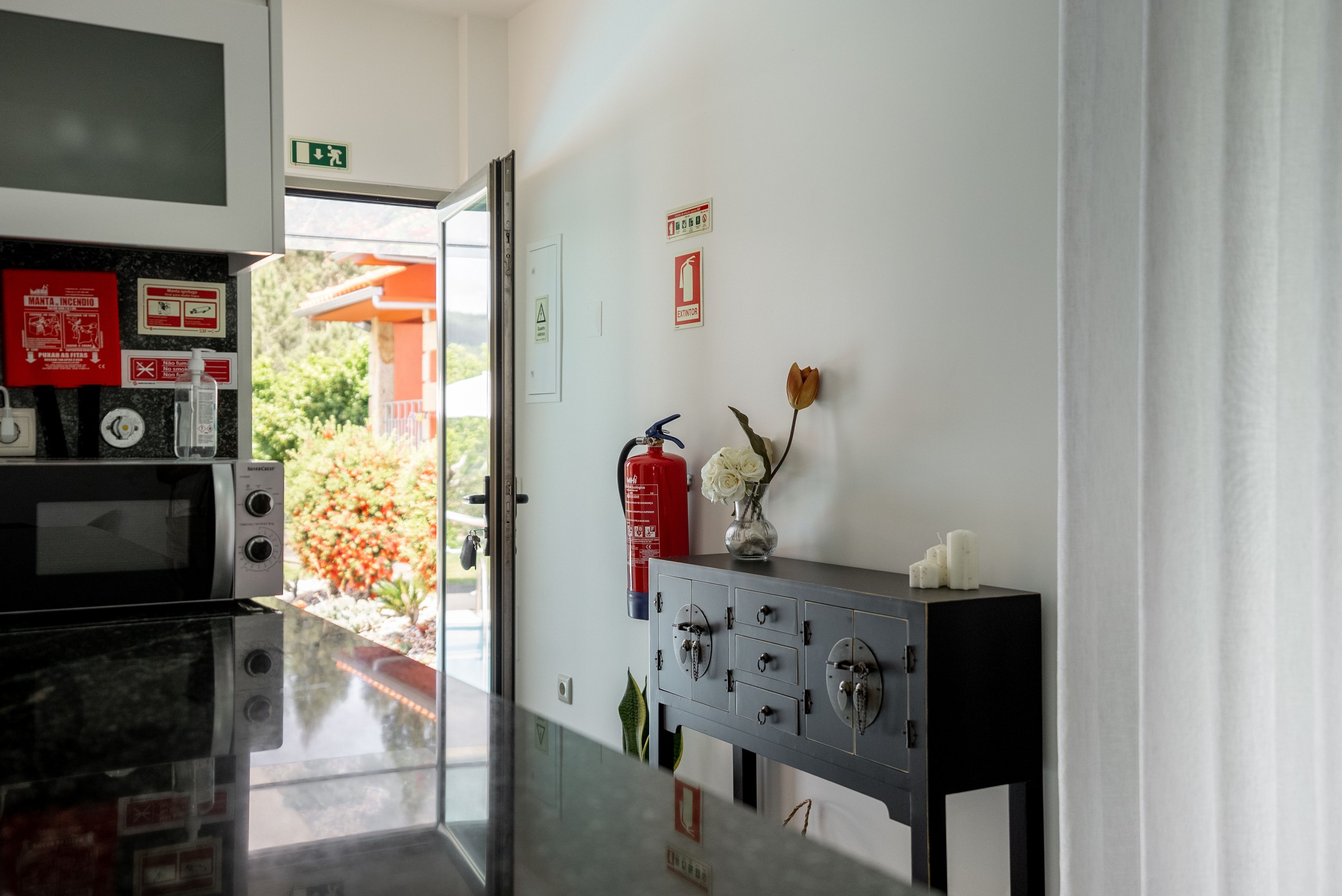 Zona de recepción de un hotel con extintor, señal de salida de emergencia en la pared y un archivador con llaves.