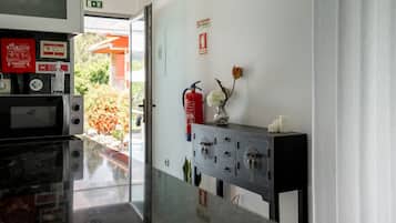 Zona de recepción de un hotel con extintor, señal de salida de emergencia en la pared y un archivador con llaves.