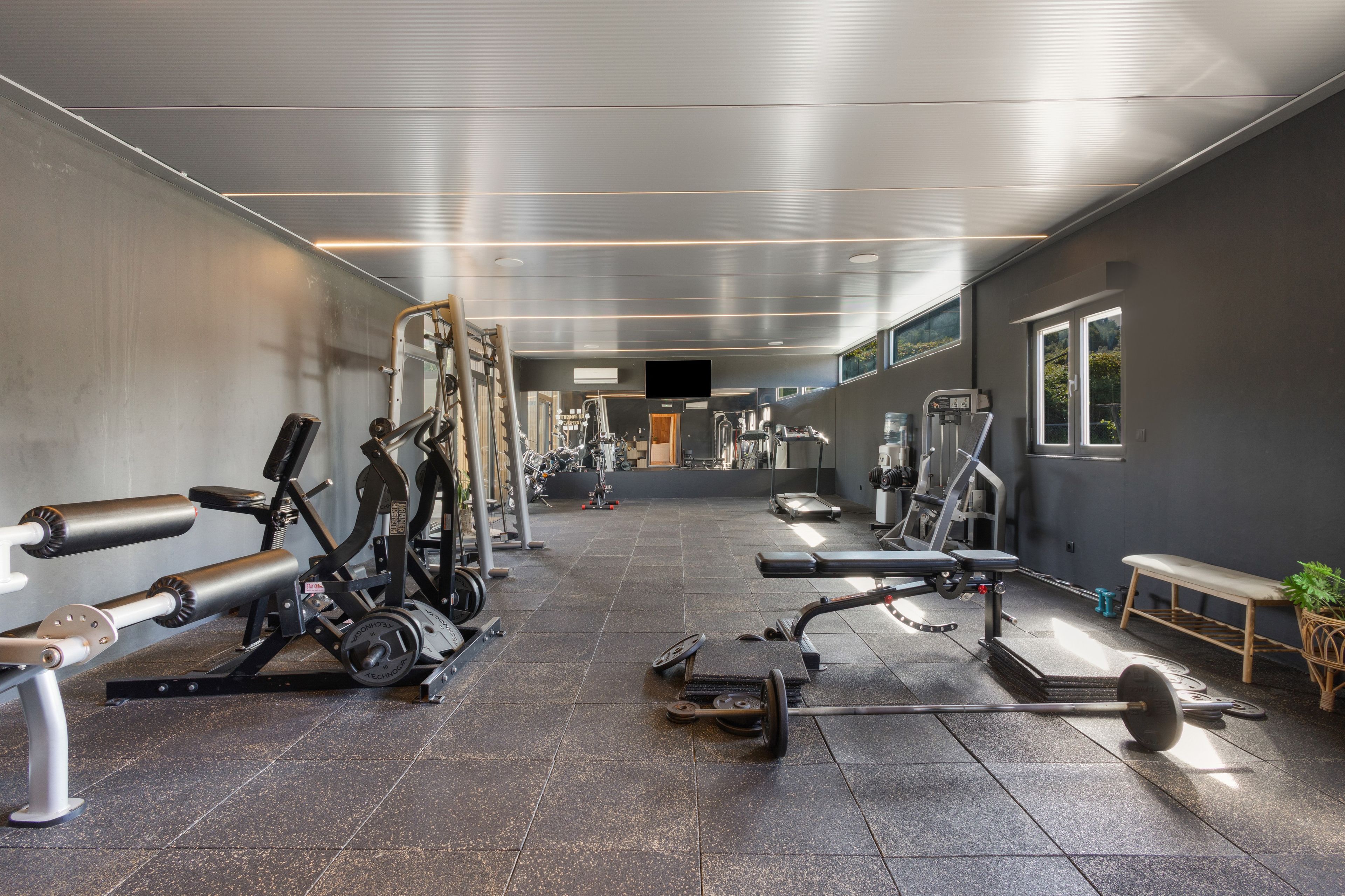 A gym with various exercise equipment, a bench, and a weight rack.