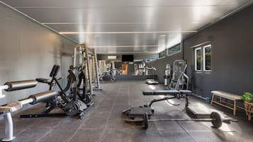 A gym with various exercise equipment, a bench, and a weight rack.