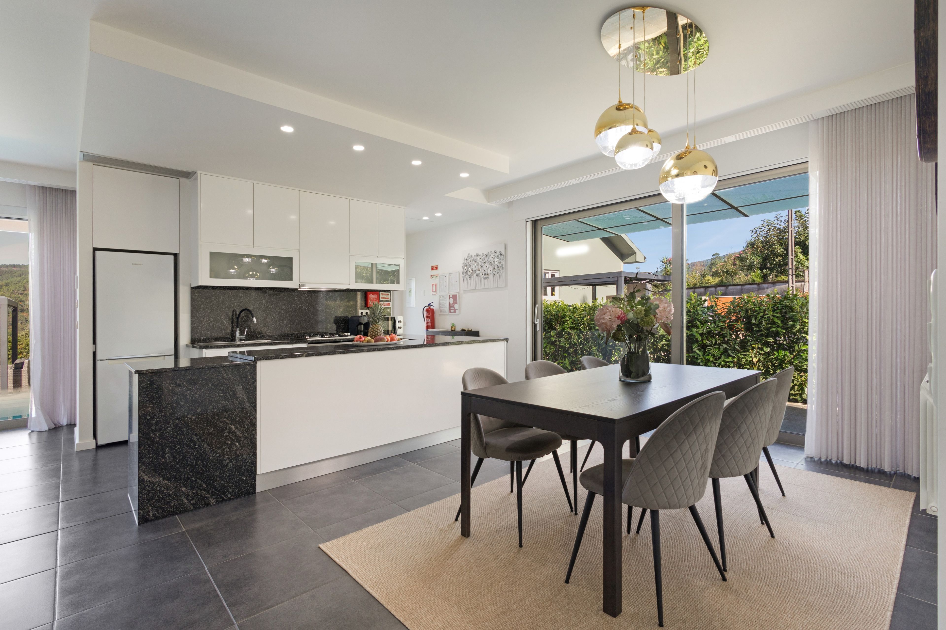 A modern kitchen with a central island, white cabinetry, and a dining area with a table and chairs.