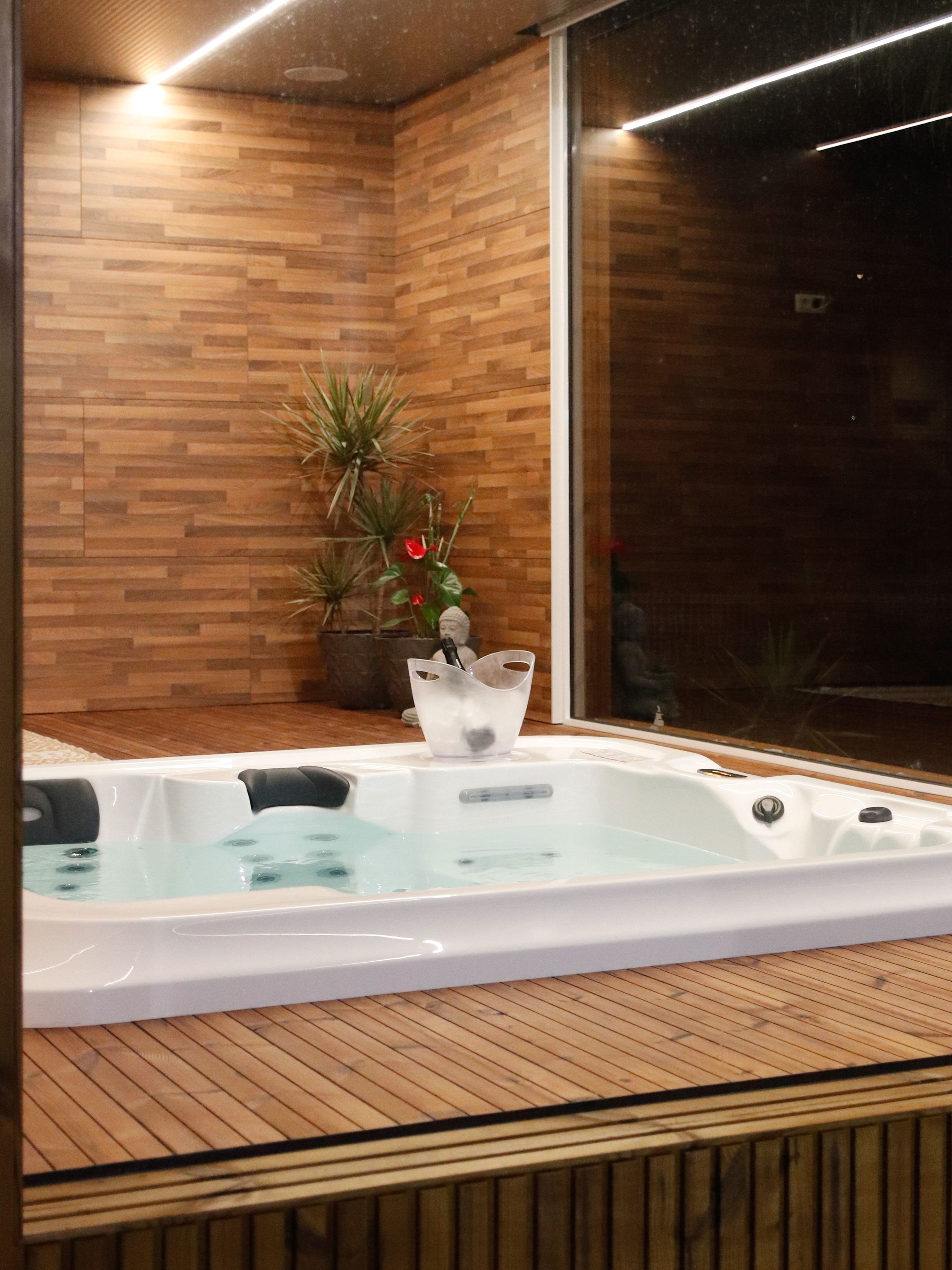 Ein Whirlpool in einem Raum mit Holzboden und Backsteinwand.